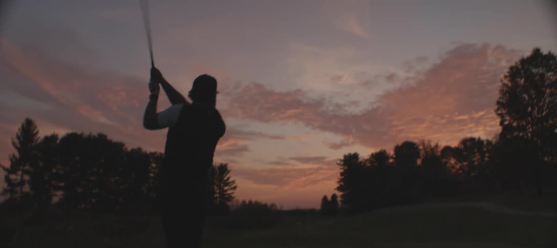 A clip of a person playing golf silhouetted against a beautiful sunset