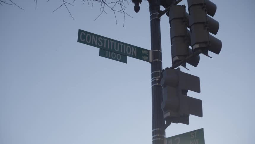 A street sign for constitution avenue against a clear blue sky