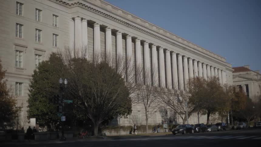 A partially obscured view shows a classical style government building in washington dc seen through a dark out of focus foreground object