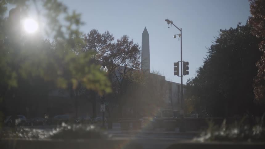 Street of an urban city in daylight with a historic pillar in the background