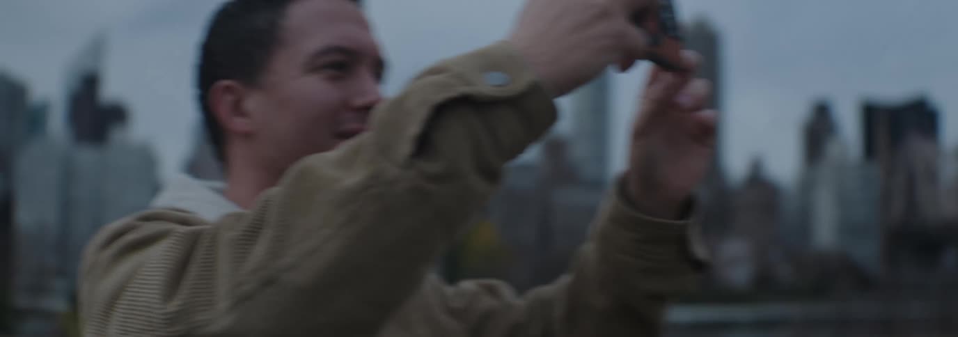 A man smiles while taking a selfie photo in a metropolis on an autumn day
