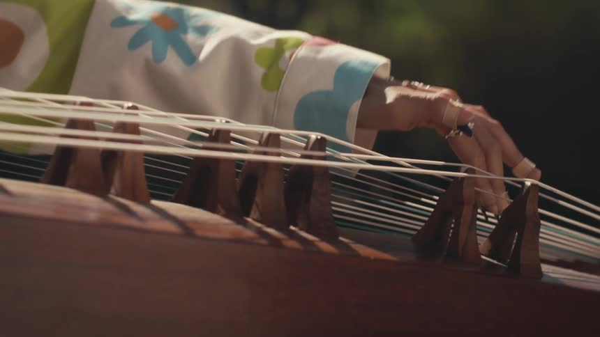 A woman playing a traditional chinese instrument