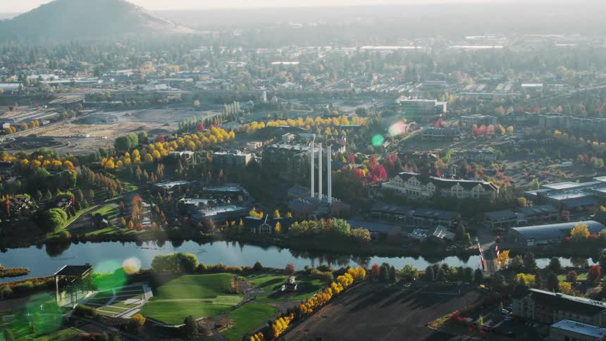 An aerial view of bend oregon featuring a river park autumn trees and the distinctive smokestacks of the old mill district