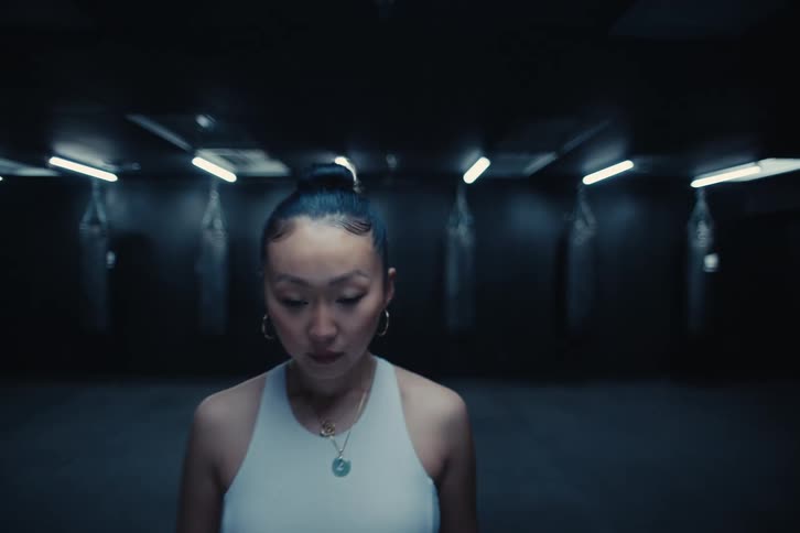 A woman walks forward in the dark gym