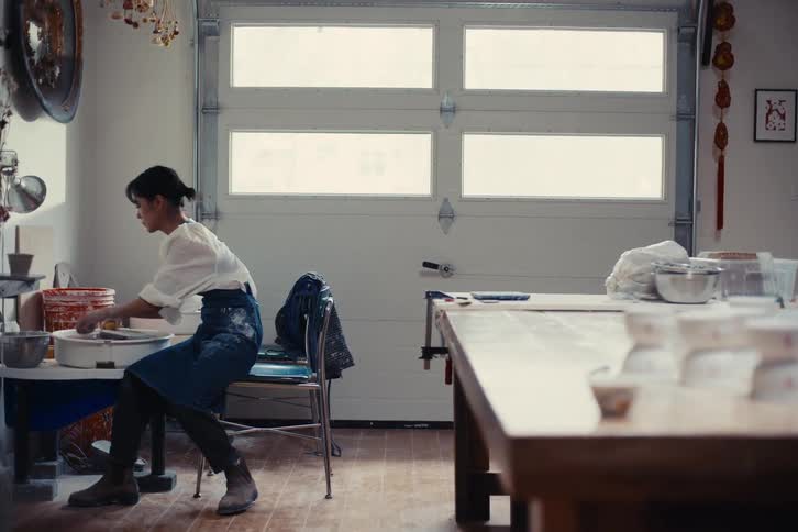 An artist works in a welllit workshop creating ceramic pieces