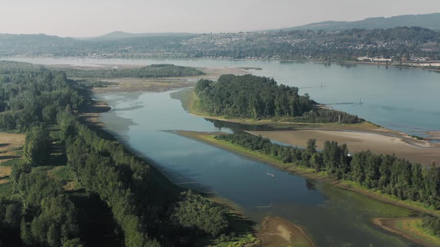An aerial view of a river delta with a network of waterways islands and marshlands surrounded by lush green vegetation