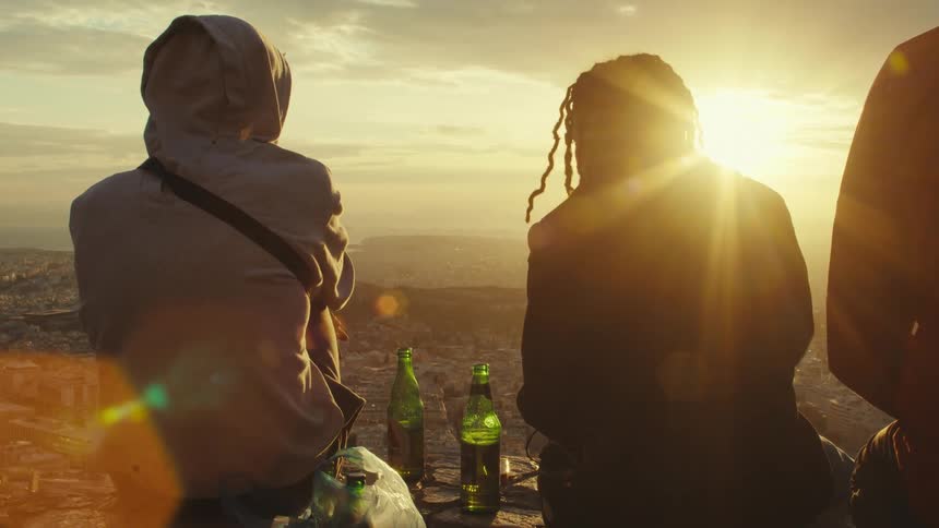 Group of friends sitting with elevated cityscape and bottles of beer