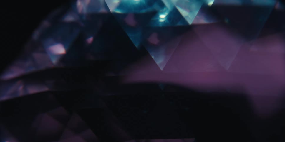 Faceted triangles ofa gem rotate and change colors under a light