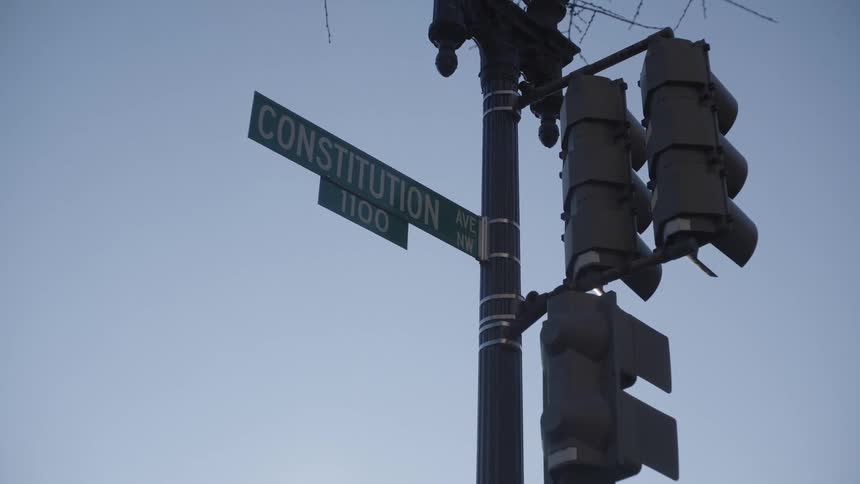 A street sign for constitution avenue against a clear blue sky