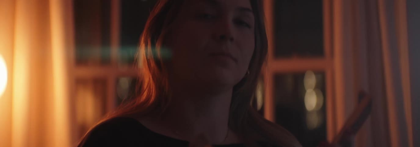 Closeup of a woman with long hair applying makeup at home at night
