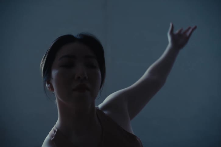 Young woman in an indoor space with arms outstretched dancing