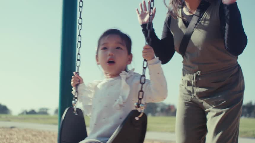 Mother swinging her daughter on a toy outdoors