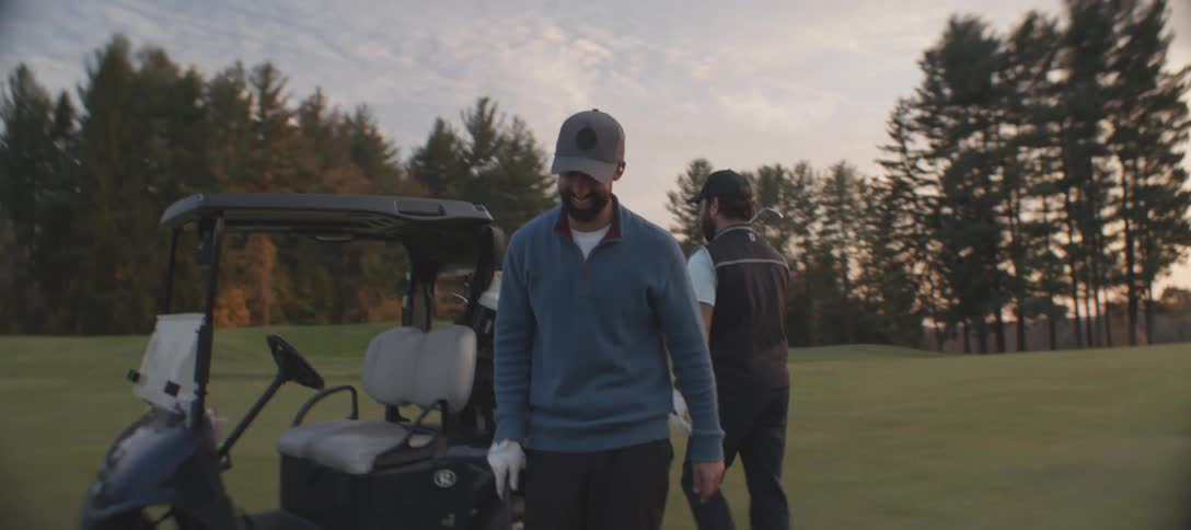 Two men on a field with one of them holding a golf club