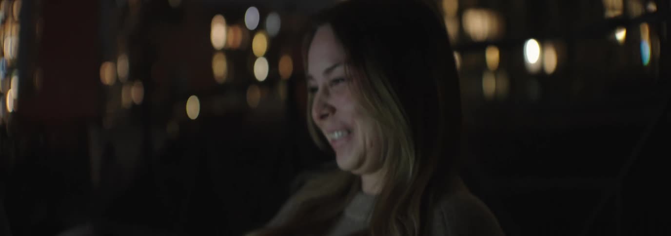 Woman sitting outdoors at night happily interacting with a laptop