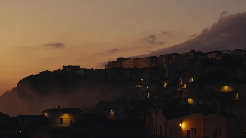 The cityscape of a town built into a cliffside at dusk or dawn