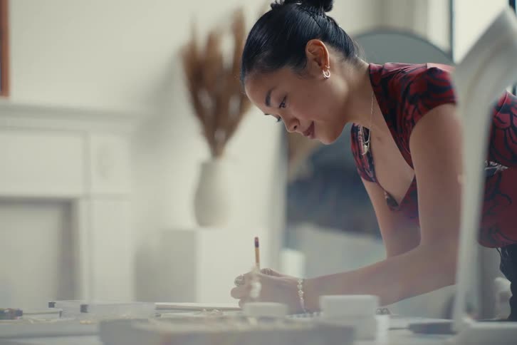 Woman standing in a room writing with a pencil