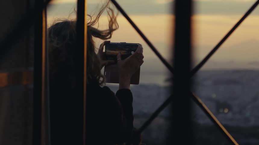 A clip of a lady operating her phone at the balcony