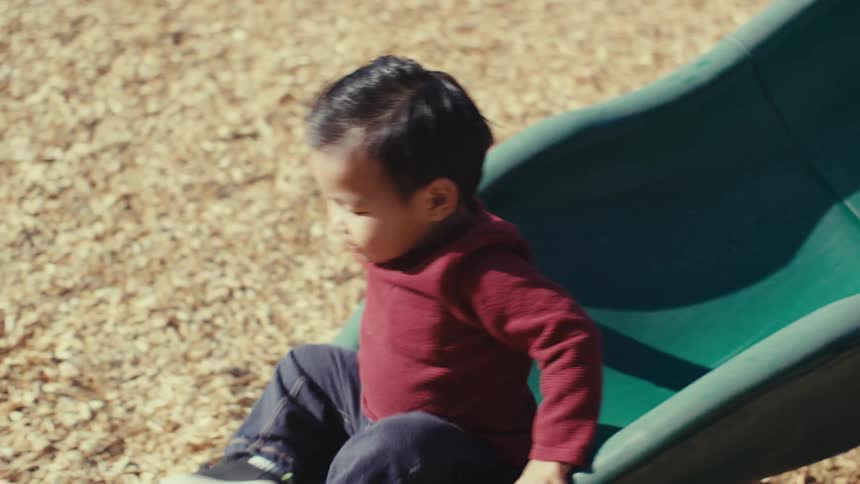 Boy playing in a playground sliding on a toy