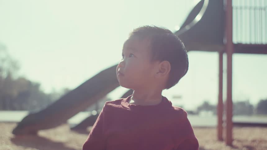 A child waves and smiles on the playground