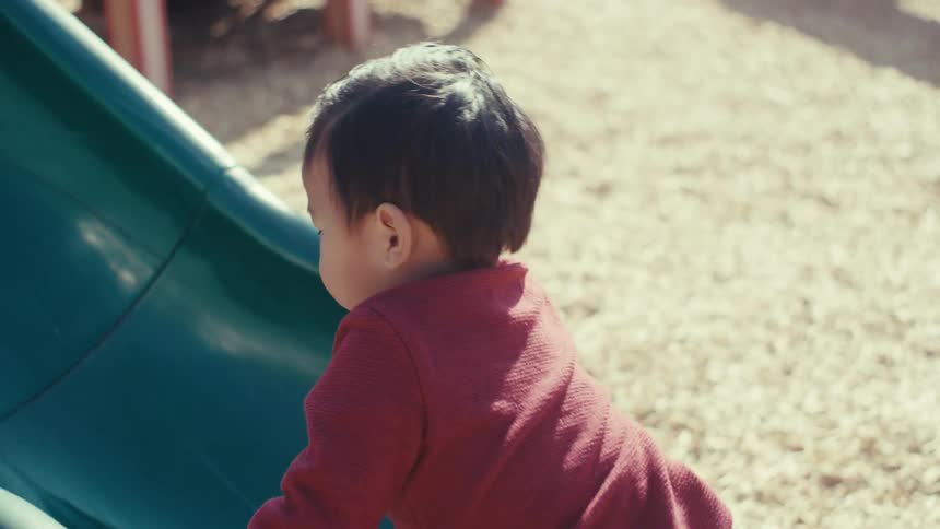 A child is climbing up the slide in the playground