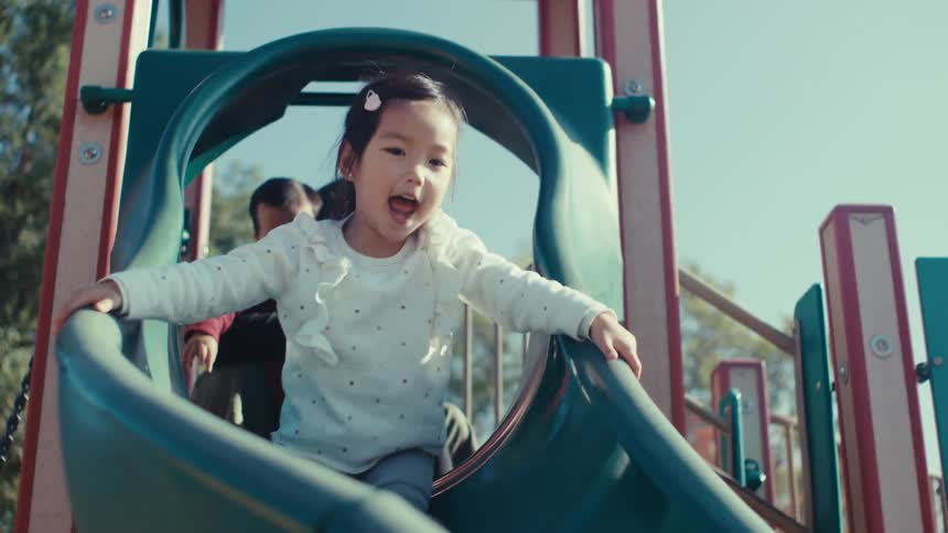Little girl having fun sliding down an outdoor toy slide