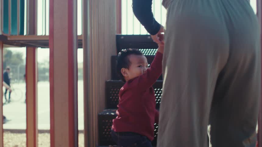 A mother helps her child climb the steps in the playground