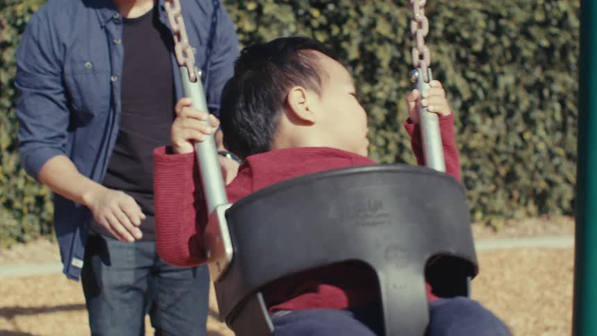 Father pushing his young son on a swing outdoors
