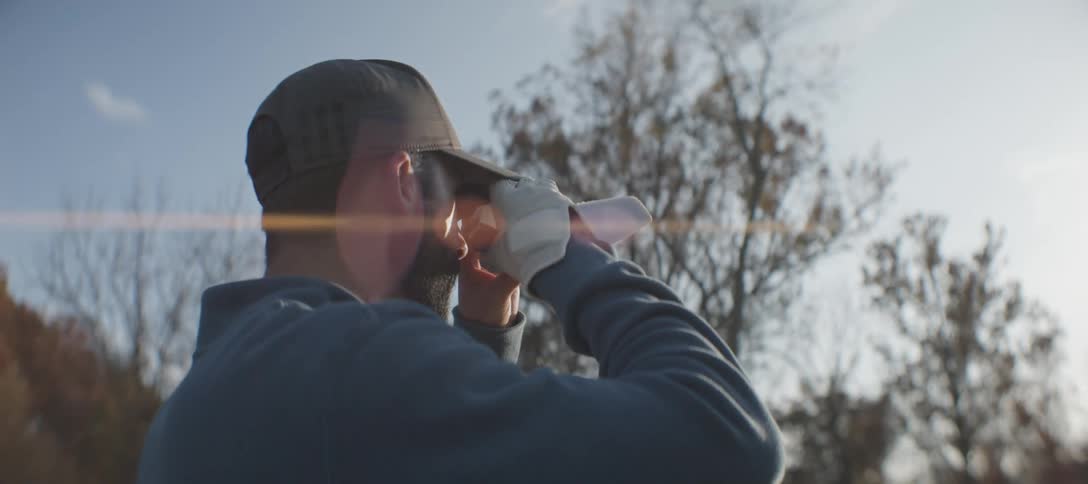Man outdoors looking through binoculars