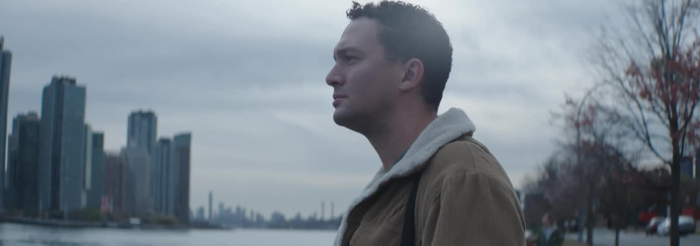 A man is viewing the skyline from across the water