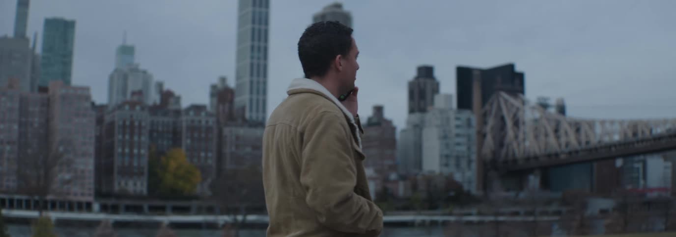 Man in a brown coat walking and talking on a phone call