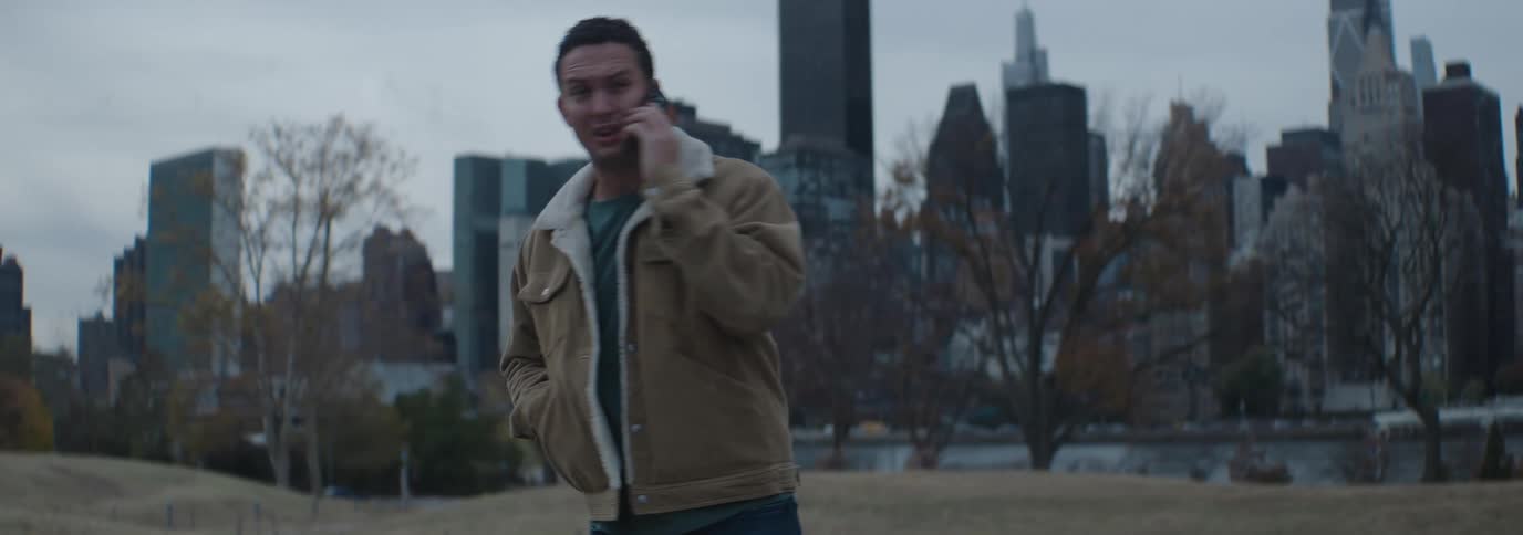 Man walking back and forth talking on his cell phone and in the background skyscrapers in a metropolis