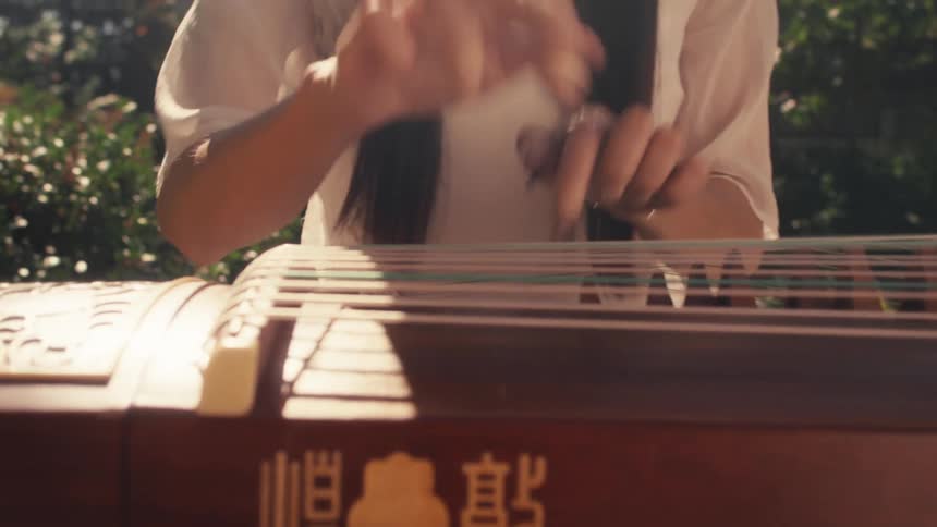 A woman playing a guzheng a traditional chinese plucked string instrument with 21 strings