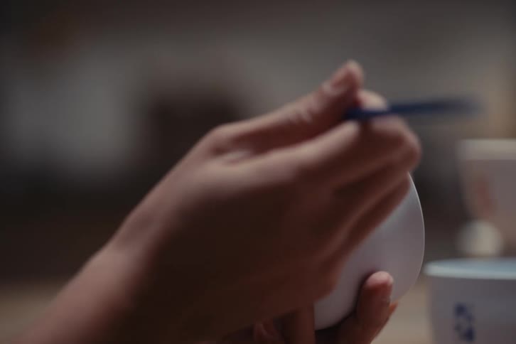 Pair of hands artistically drawing on a white mug