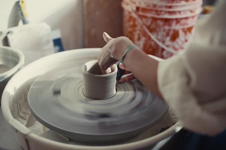 A potters hands skillfully shape a vessel of clay on a spinning wheel their fingers guiding the material into a graceful form