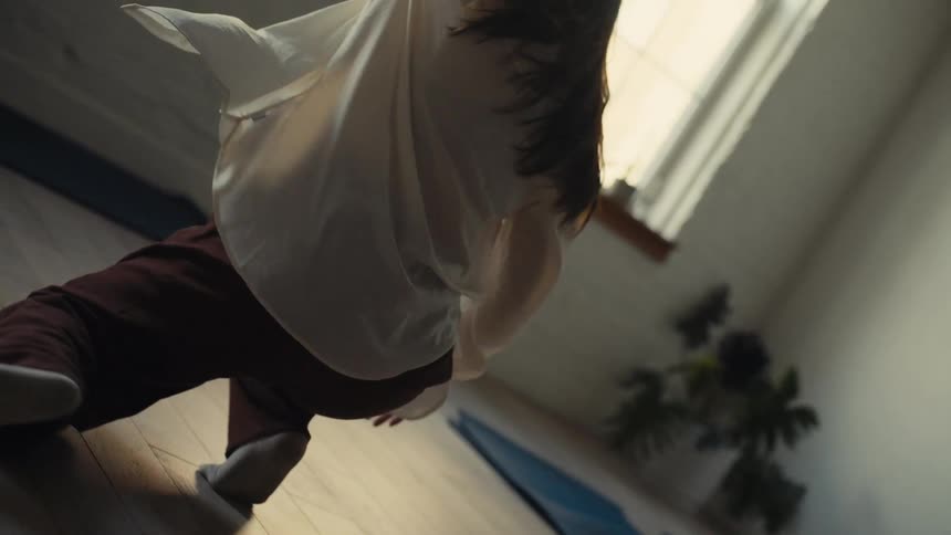 A woman dances on the floor of a sunlit room
