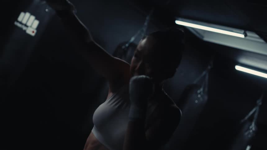 Determined woman training boxing punches at gym
