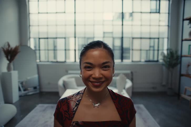 Woman smiling while standing in a living room with a window in the background