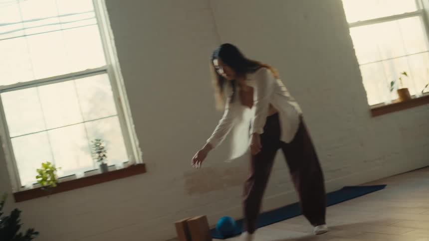 A woman dances in a welllit room with bright sunlight filtering through the windows