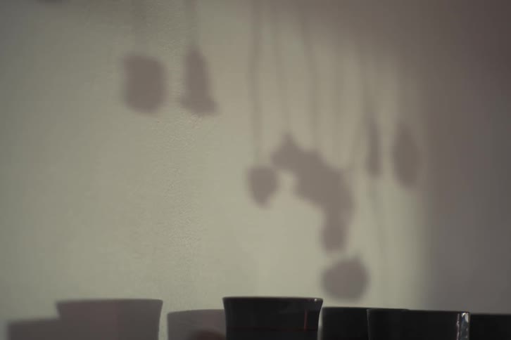 Shadows of small hanging ornaments and decorations cast onto a wall