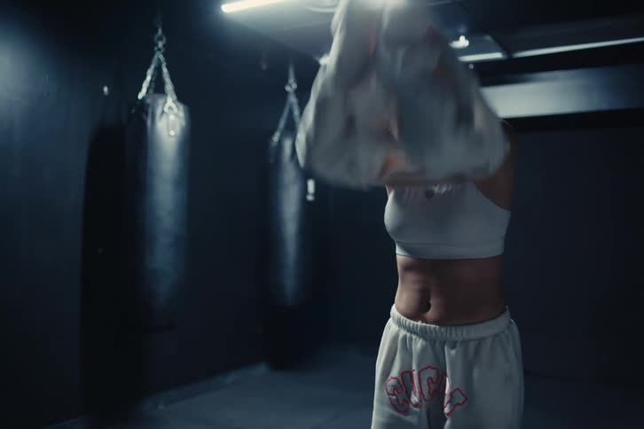 Woman in a fight gym room putting on a sweatshirt