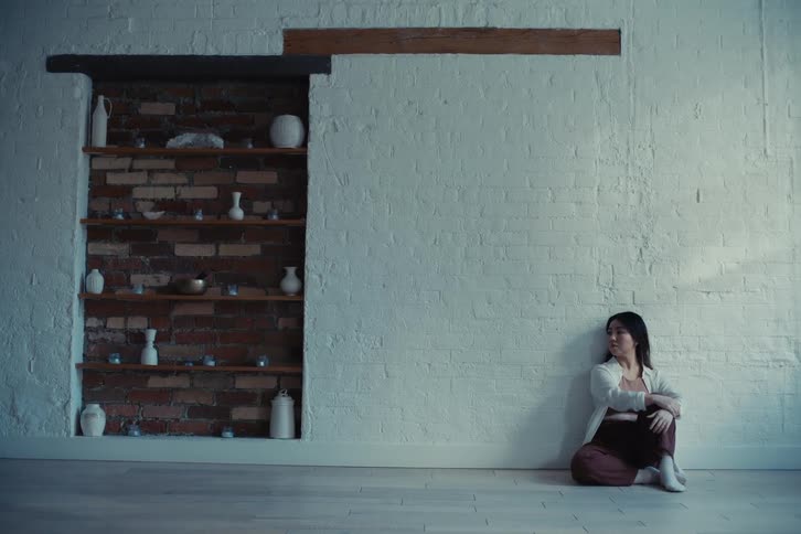 Woman sits on the floor near shelves built into the wall