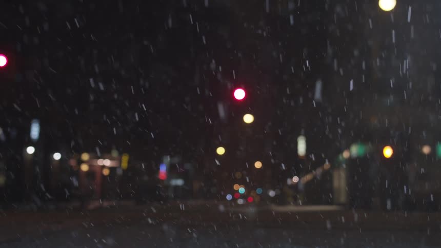 Snow falls in the city at night