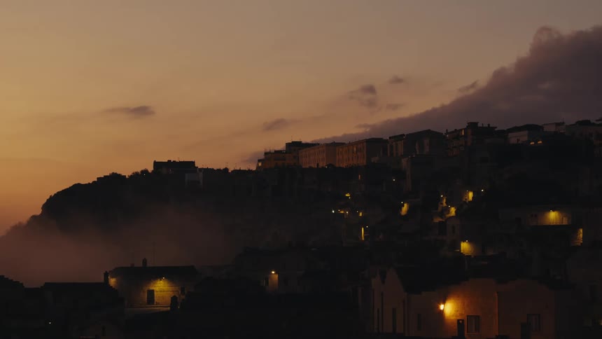 Classic houses built on ruins and mountains seen in a purple and orange sky dawn