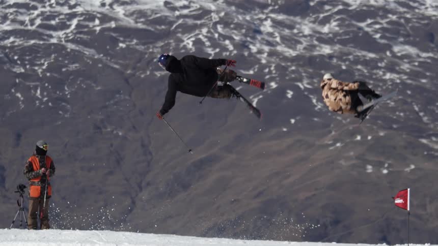 Man skiing up a slope to do a jump as others are jumping as well
