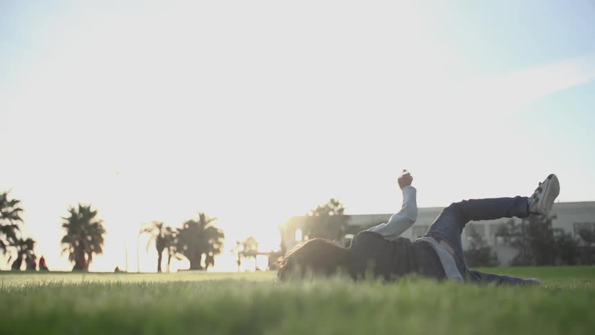 A child rolls in the grass on a sunny day