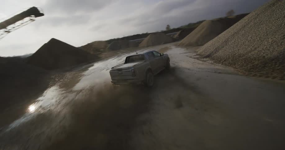 A pickup truck is driving through a muddy and challenging off road terrain