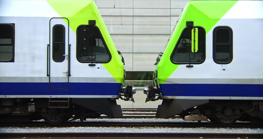A train next to a station moving away from another train outdoors during daytime