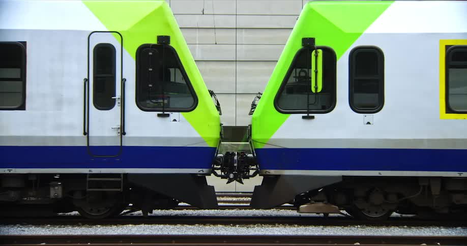 Two modern symmetrical train cars disconnecting
