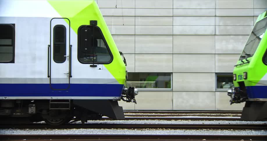 Two modern green and white trains position facetoface on parallel tracks