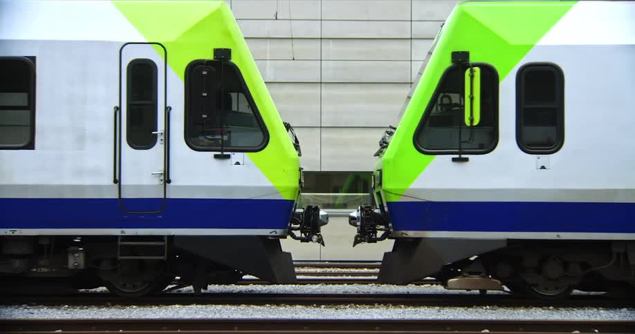 One train parking next to another on a station outdoors during daytime